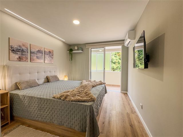 Quarto principal com cama de casal e porta para a varanda