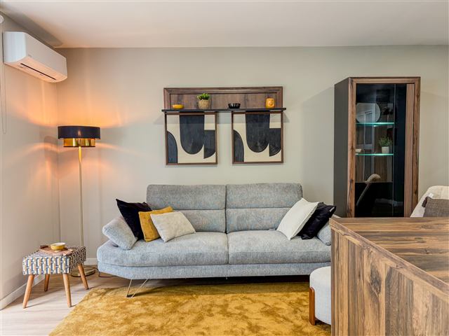 Sala de estar com sofá cinzento e candeeiro dourado